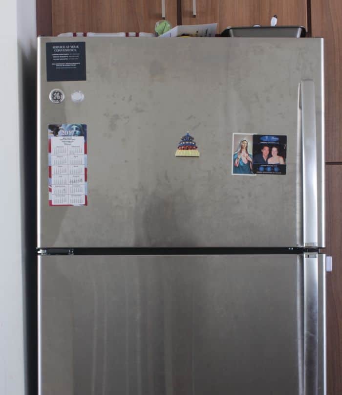A dirty stainless steel fridge, ready to be cleaned