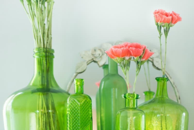 Beautiful green thrift store vases with flowers in them.