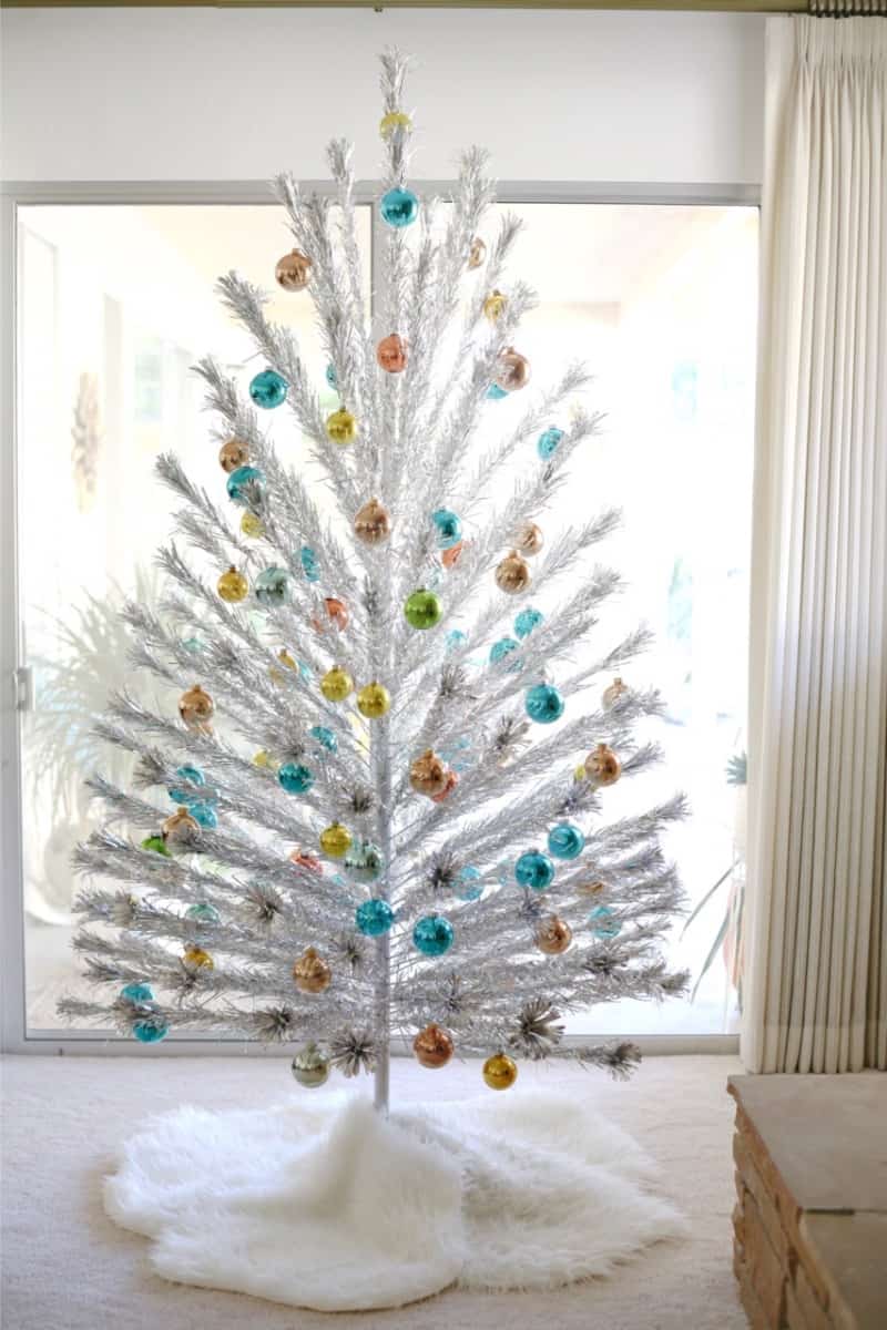 A white aluminum minimalist Christmas tree with colorful ornaments