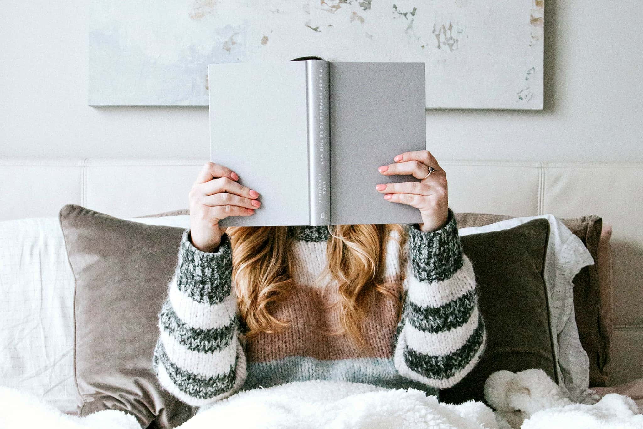 A woman reading one of the best minimalism books in bed