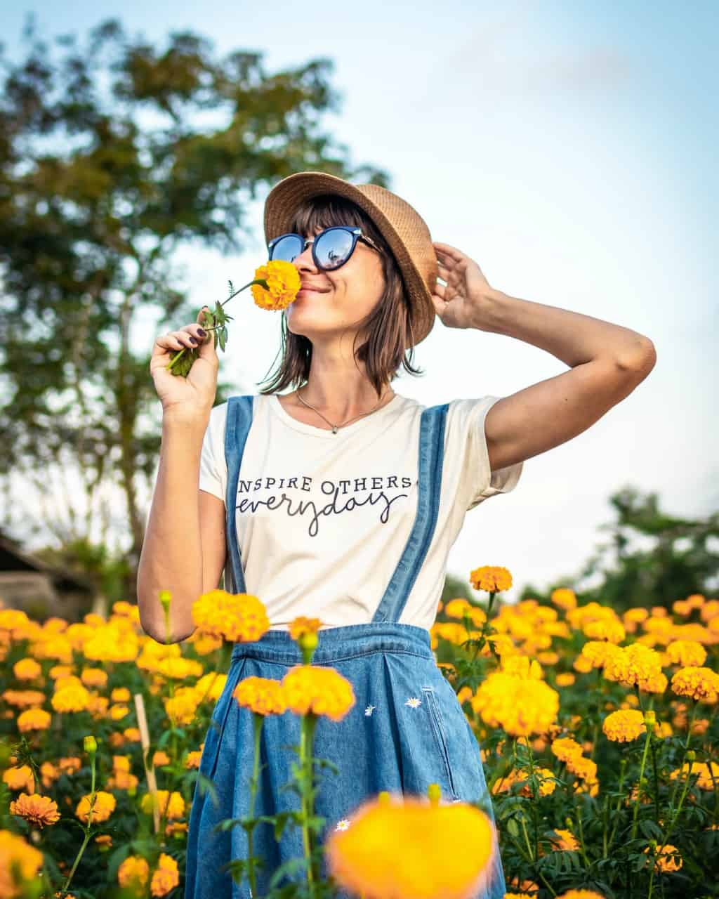 A woman smelling a yellow flower in a field