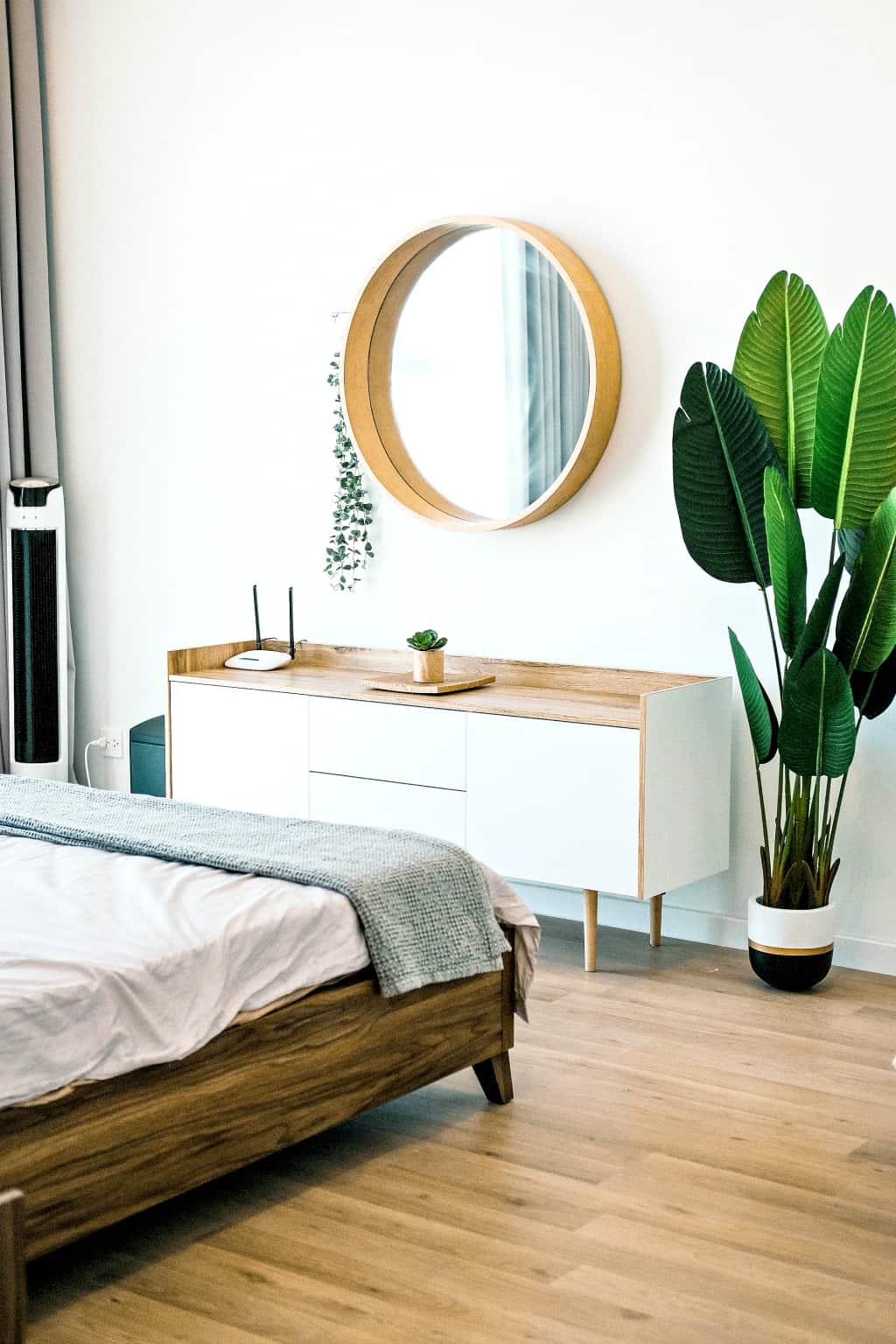 A decluttered bedroom with round mirror and plants