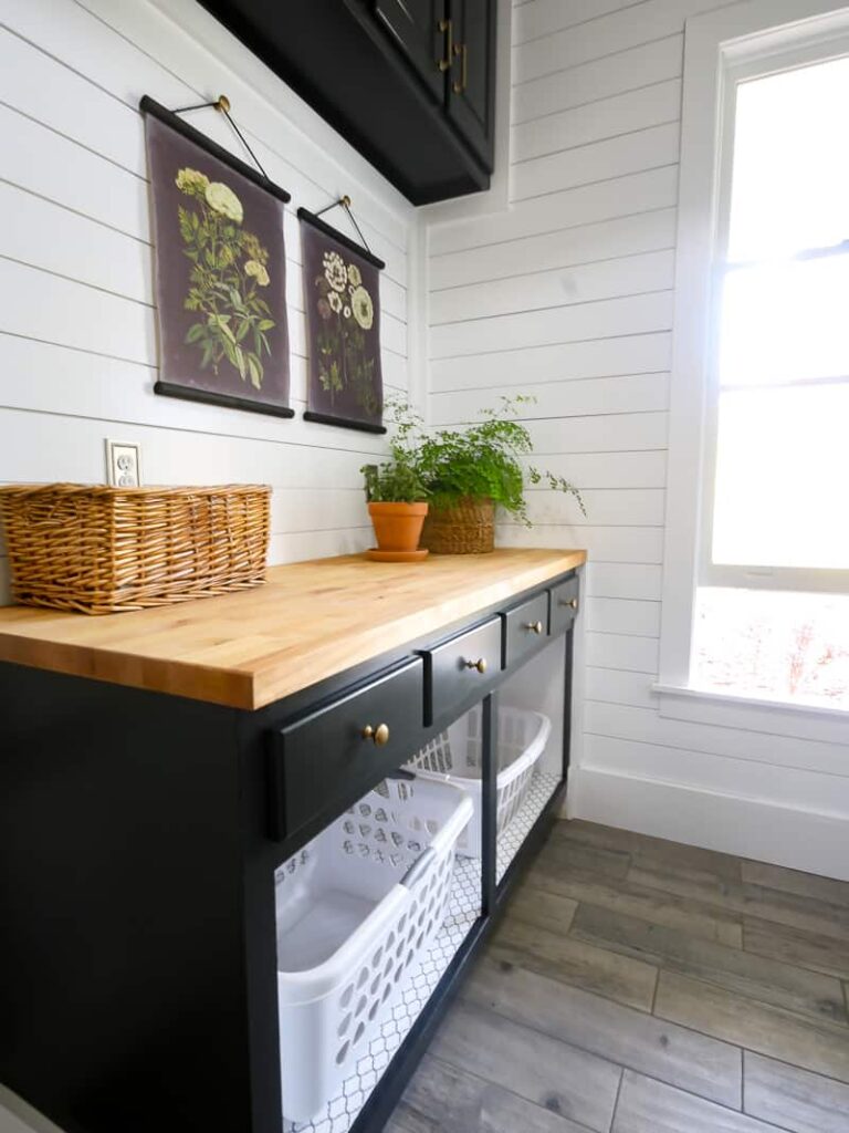 A folding table in a laundry room with laundry basket storage underneath 