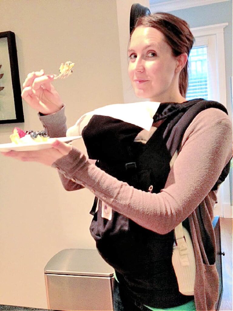 A minimalist mom eating while carrying baby