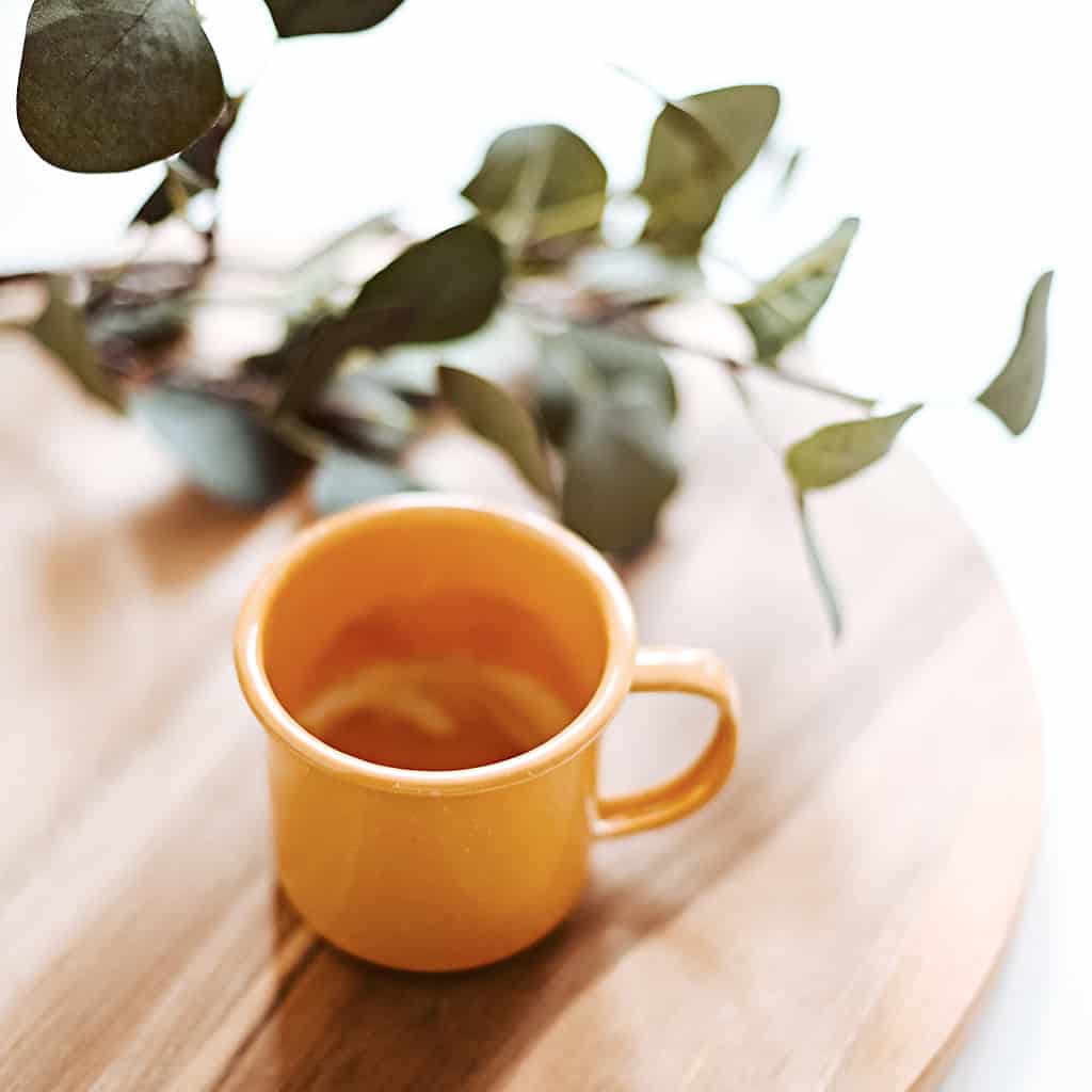 A minimalist cup of tea on a wood platter