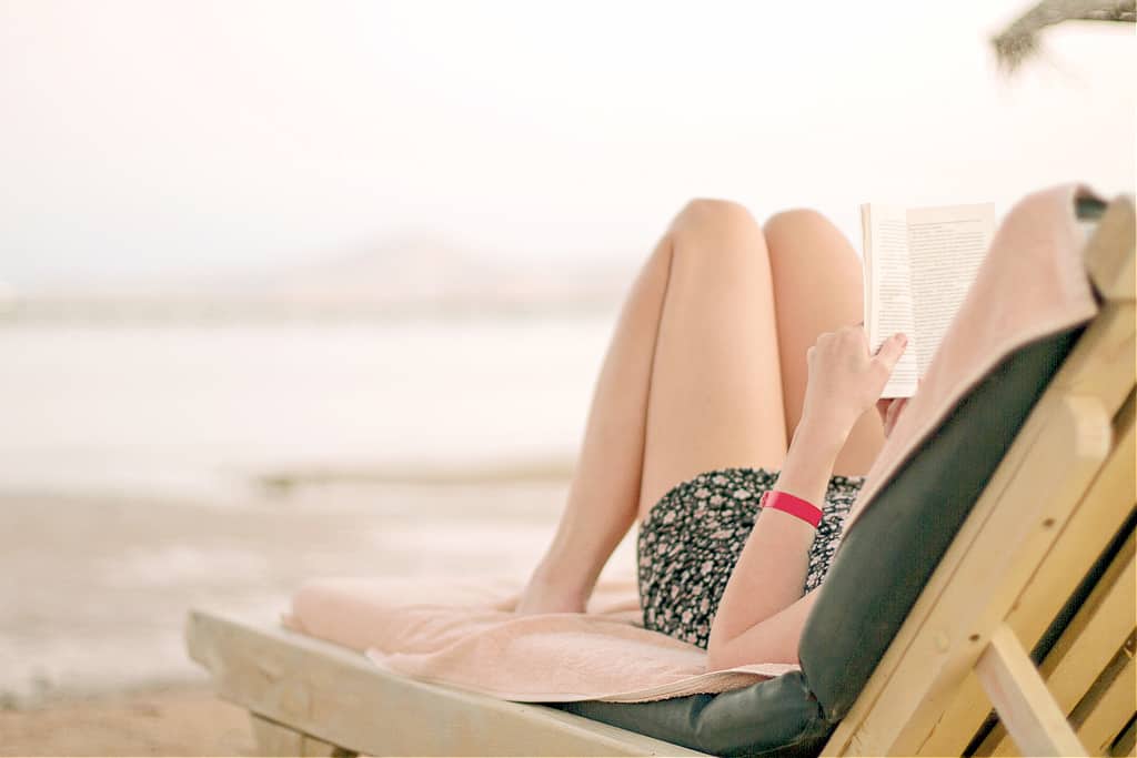 A woman reading a book on how to simplify life at the beach