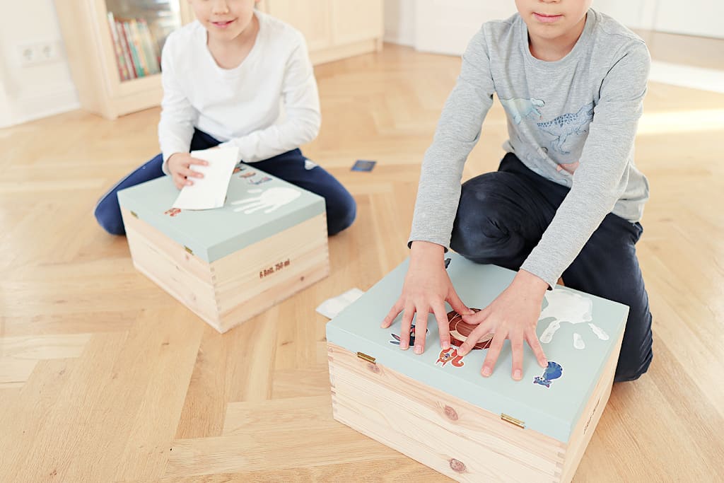 Two children showing how to decorate a memory box with stickers