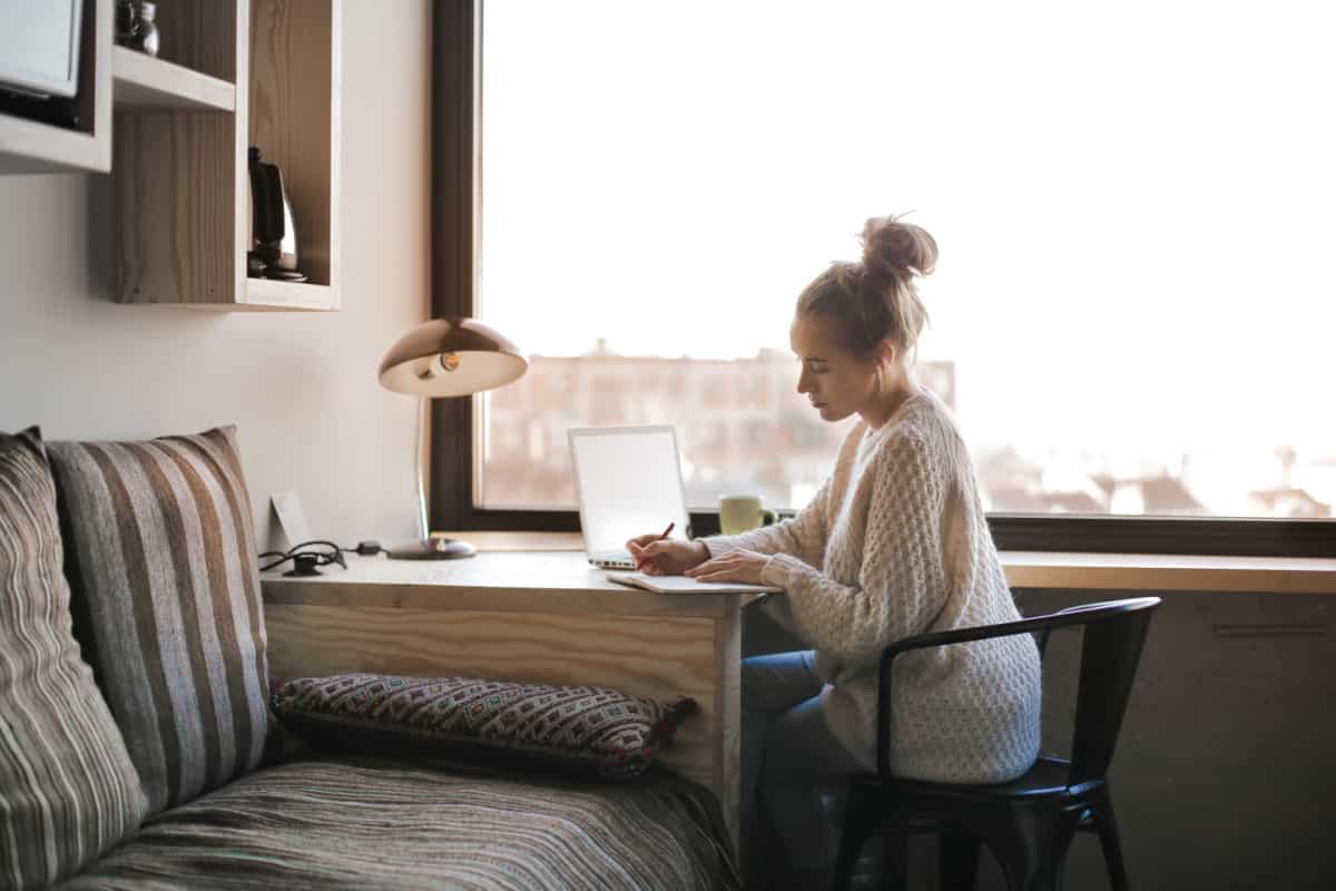 A woman writing SMART goals by a windown