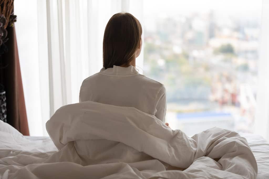 A sentimental woman in bed, quietly looking out the window