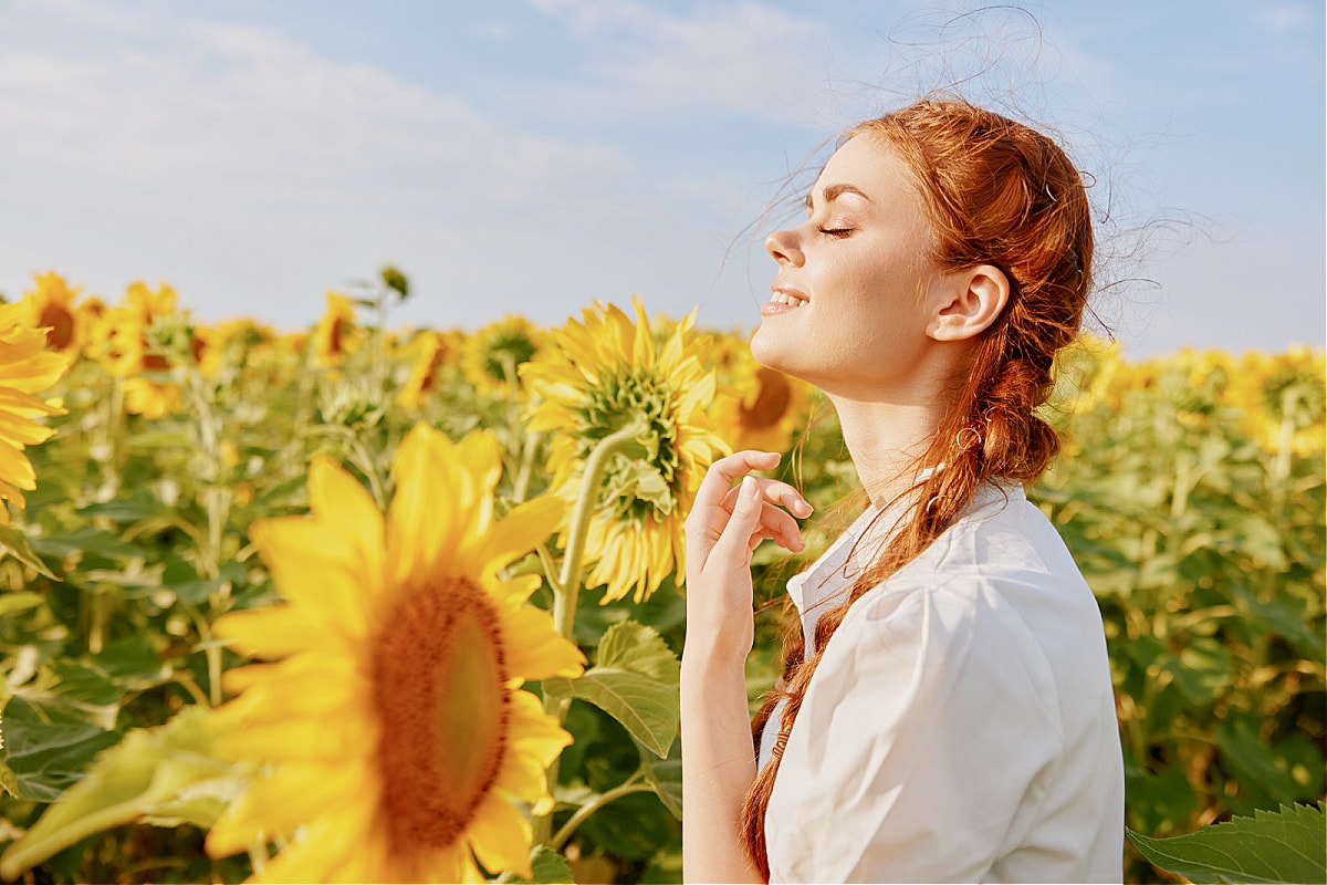 A beautiful happy person with red hair smiling in a field of sunflowers