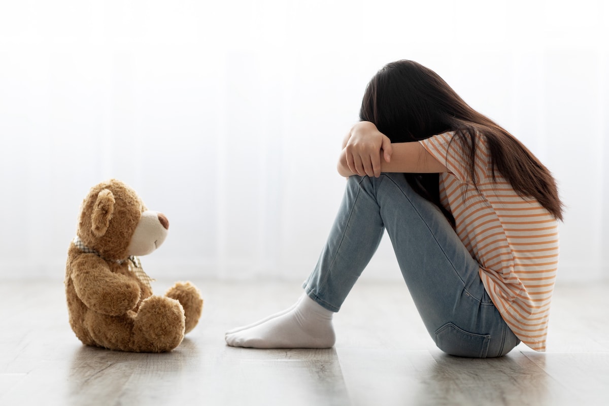 A little girl surviving a crisis with minimalism, with her teddy bear beside her