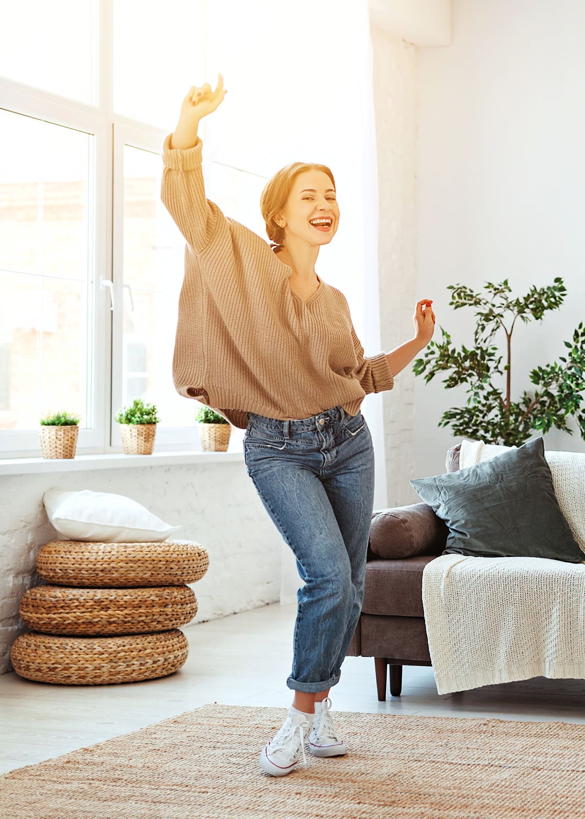 A happy person smiling and dancing at home in a beam of sunlight