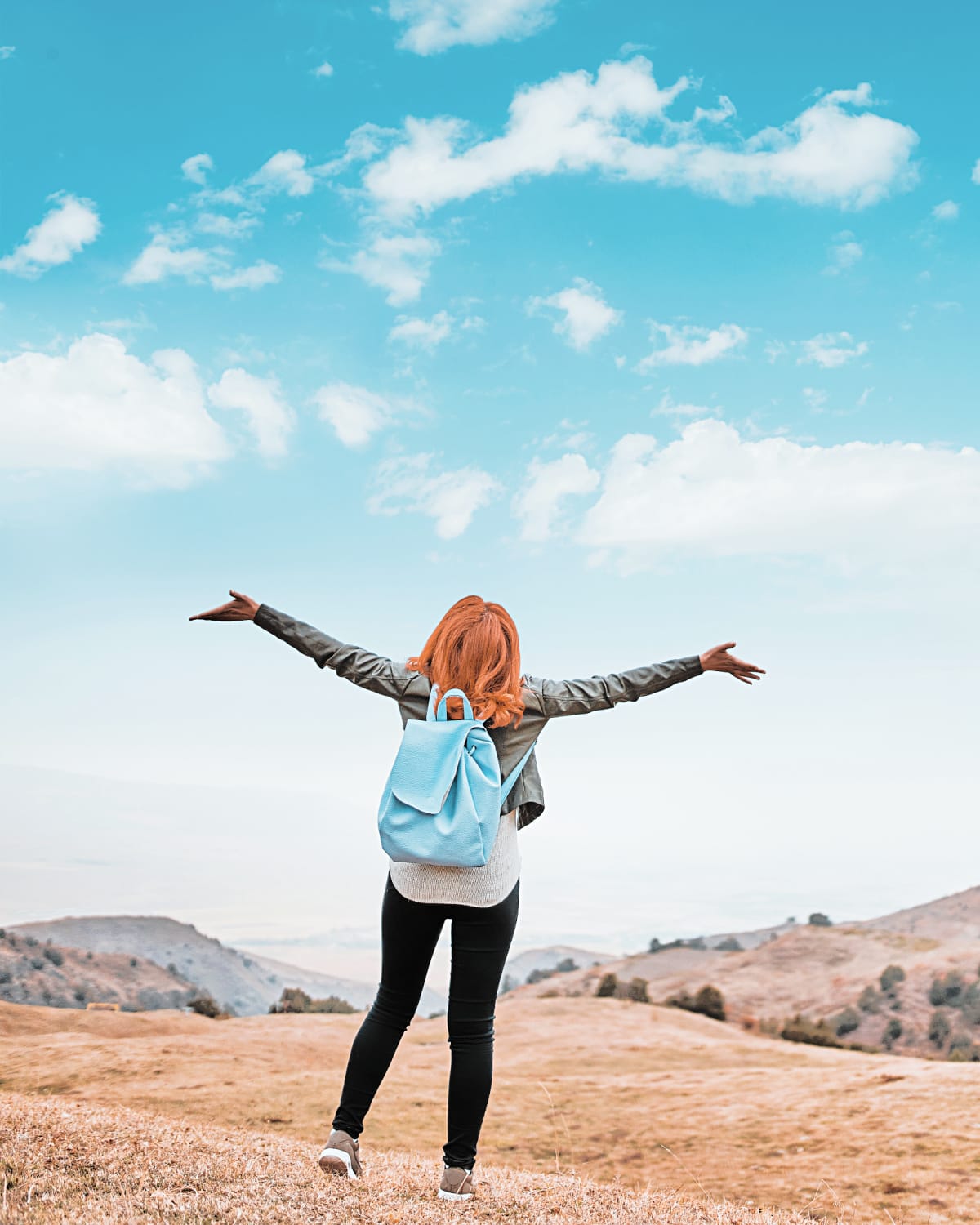 A woman happily shouting her personal motto to the bright blue sky