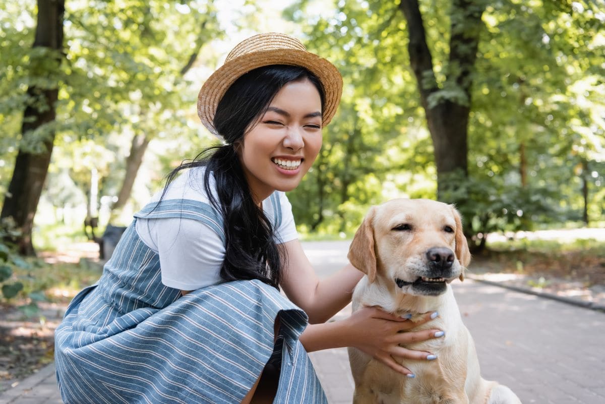 A car-free woman happily playing with her dog in the park