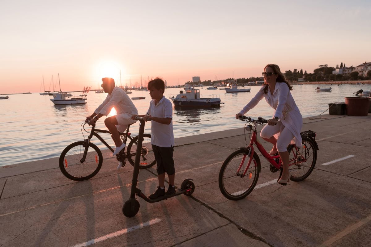 A family with no car riding bicycles and scooter and talking about how much they love driving less