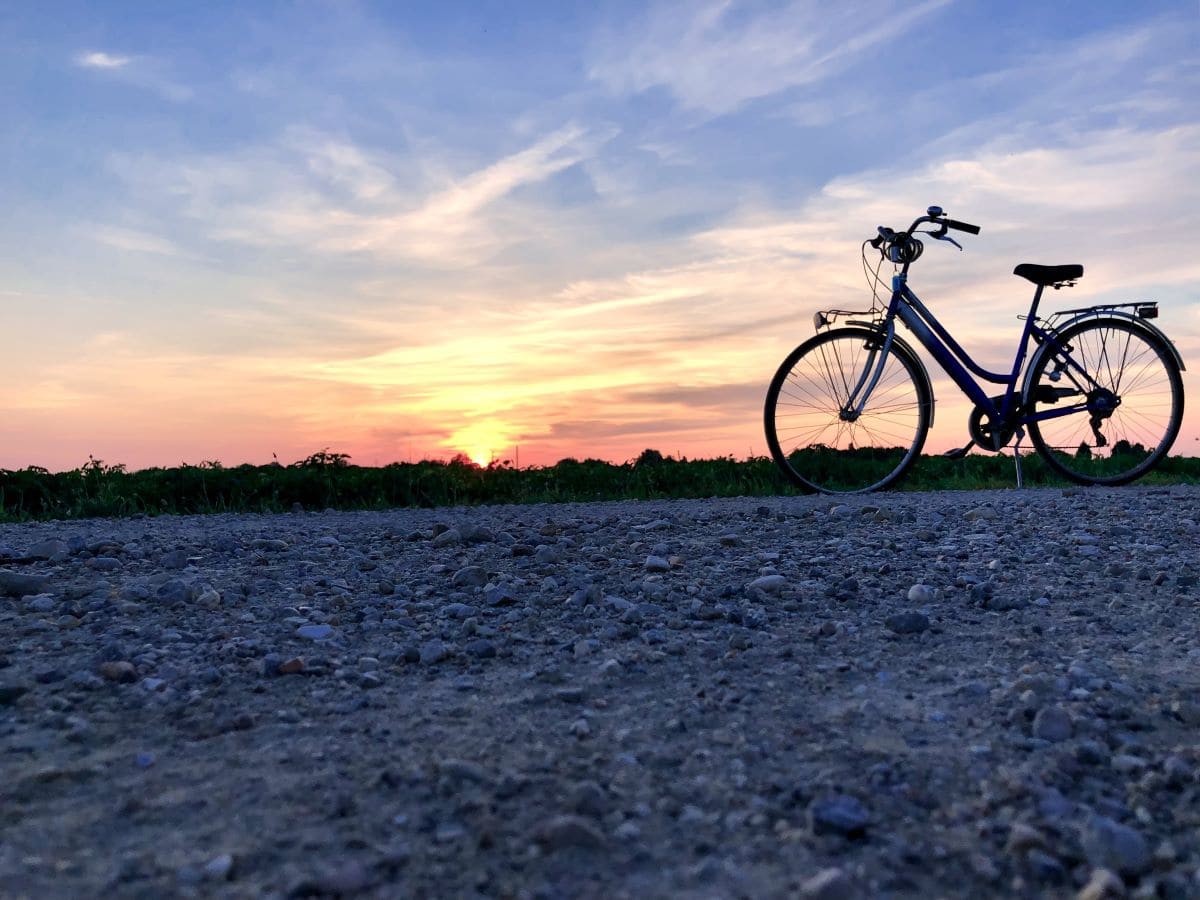 A bike and a sunset with red blue sky symbolizing freedom from driving less by car