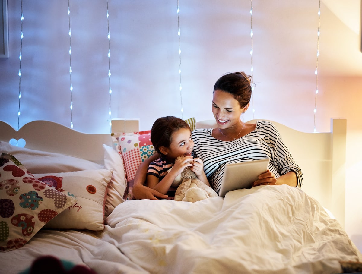 A mom and daughter doing their nightly family ritual of reading bedtime stories.