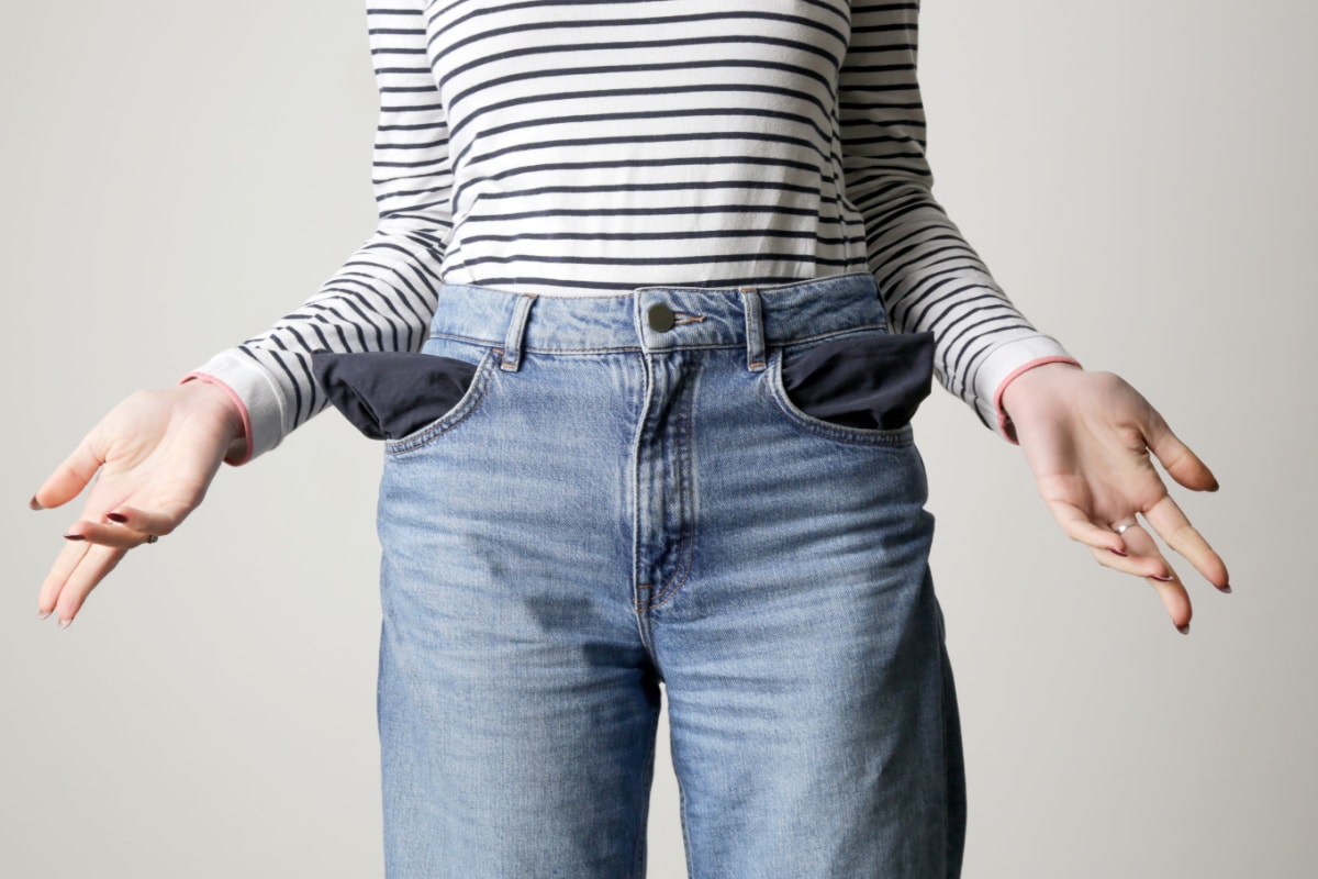 A woman in jeans with no money in her pocket after breaking her budget