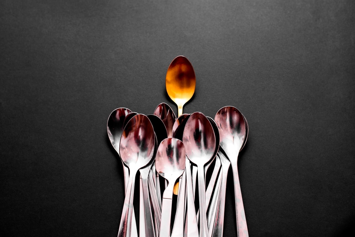 A simple gold spoon standing out above silver spoons.