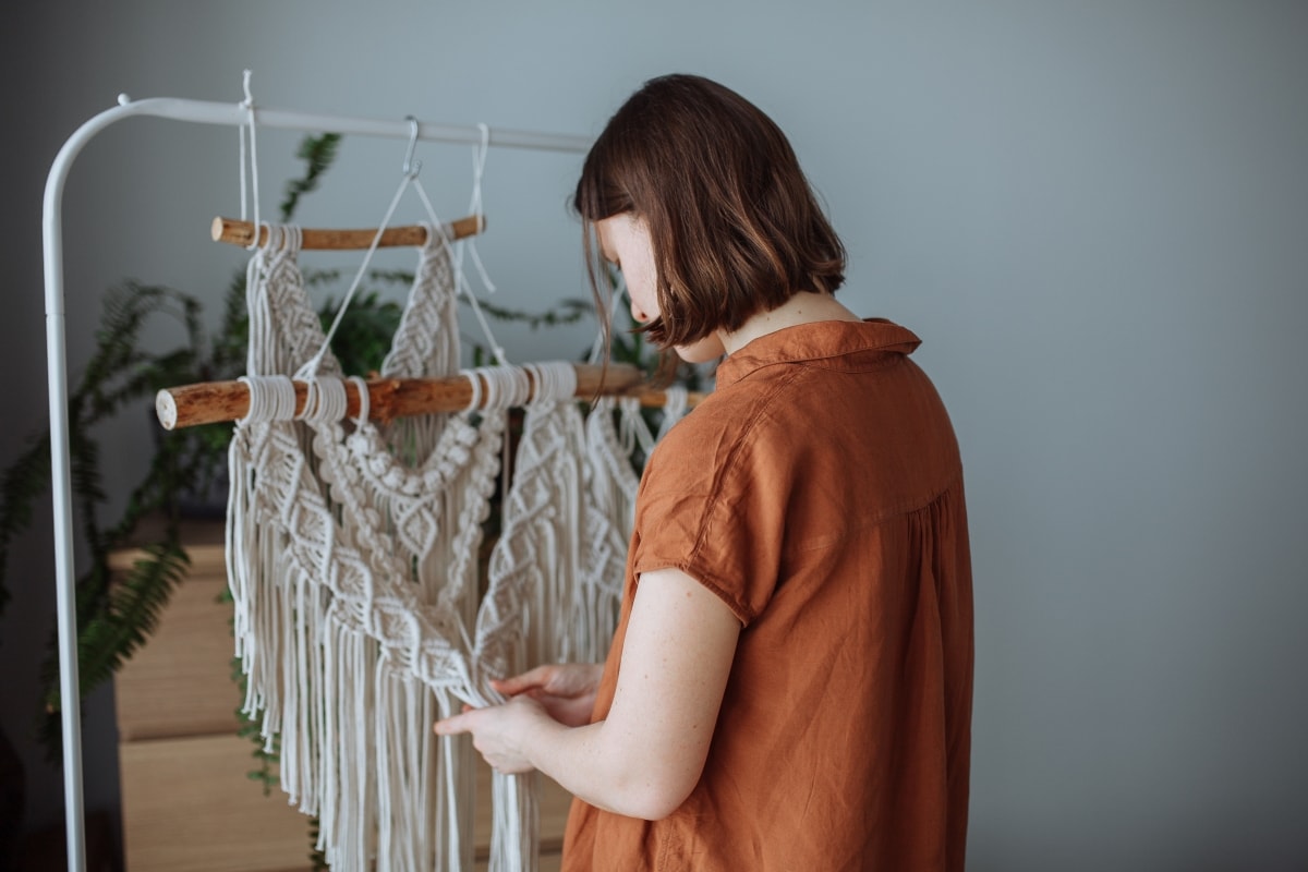 A simple woman making DIY wall decor out of macrame to put in her home.