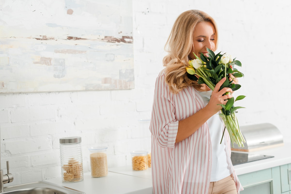 A woman smelling flowers and enjoying her quiet home
