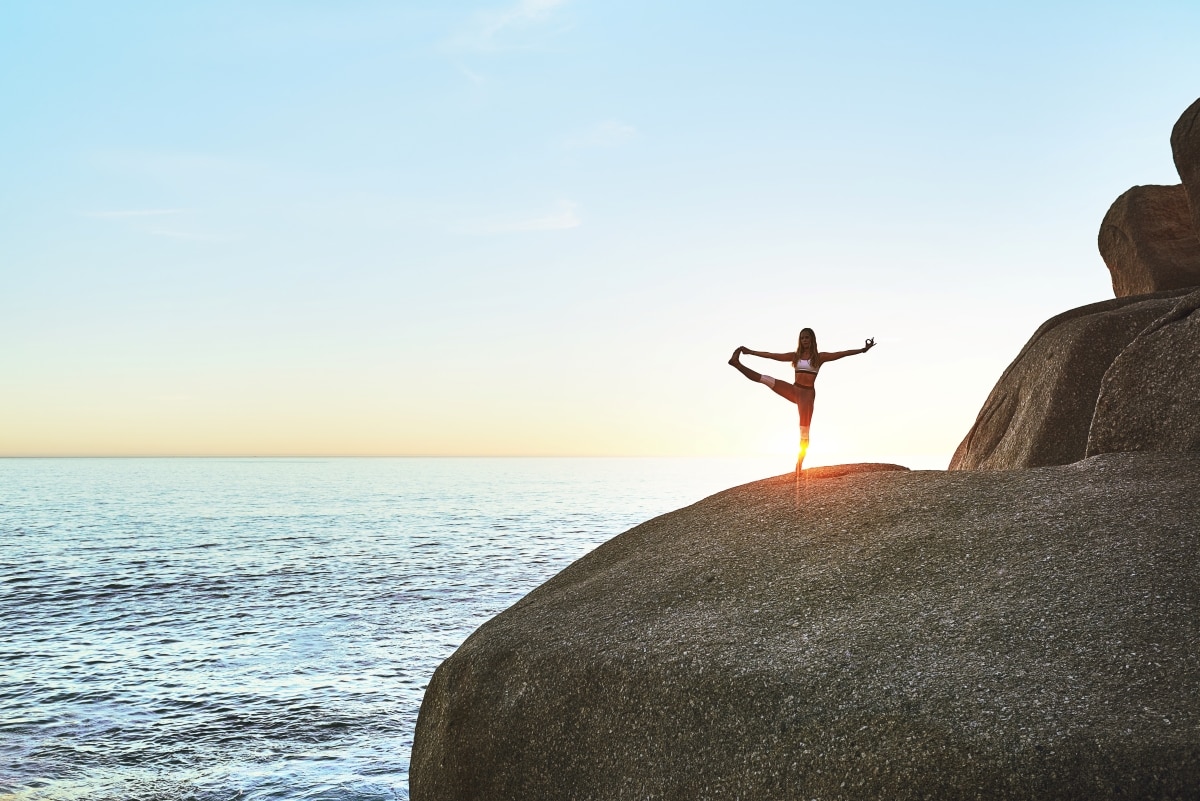 A financial minimalist women practicing yoga and peace of mind at sunrise, knowing her finances are in good order.