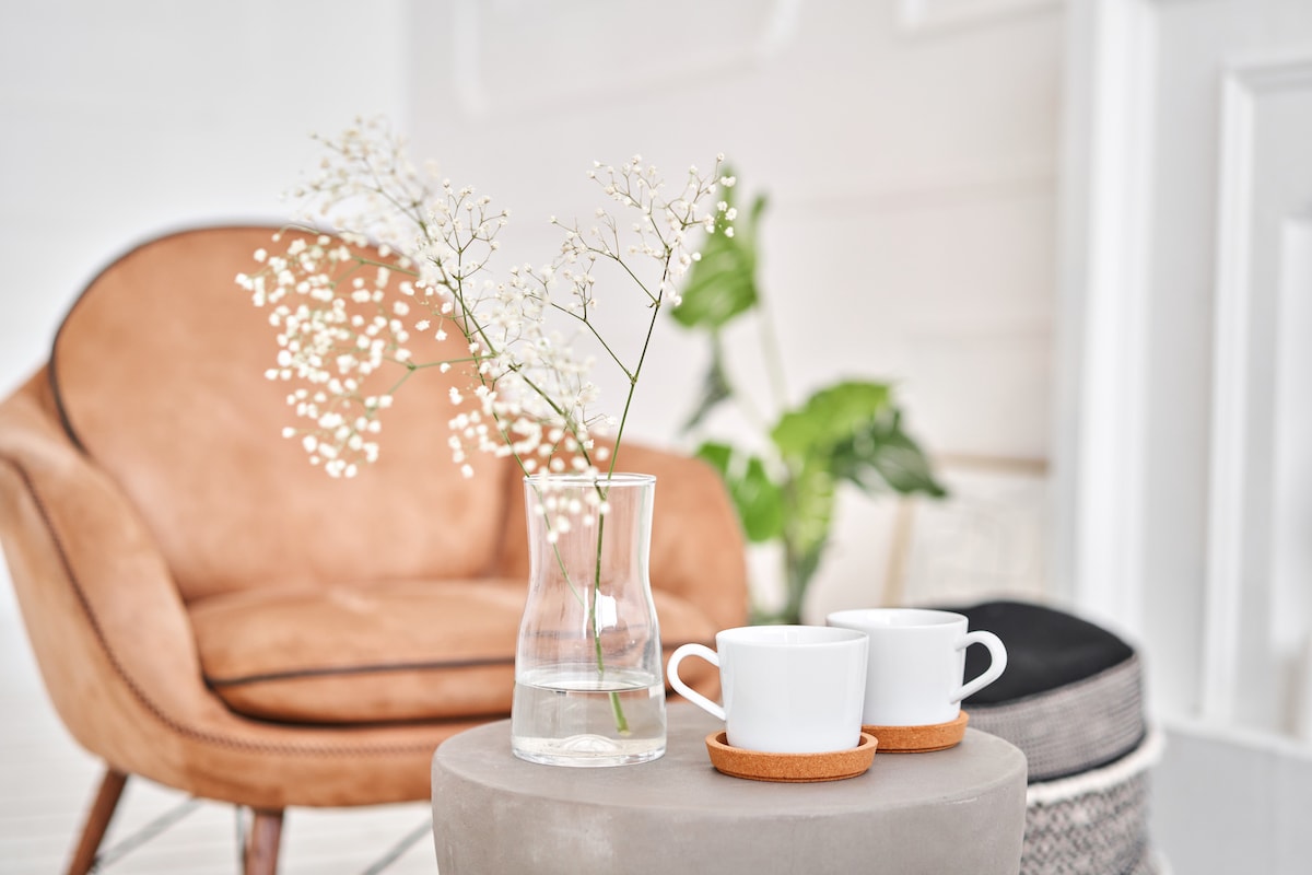 The tidy home of someone with minimalist habits, with two steaming cups of coffee and flowers nearby