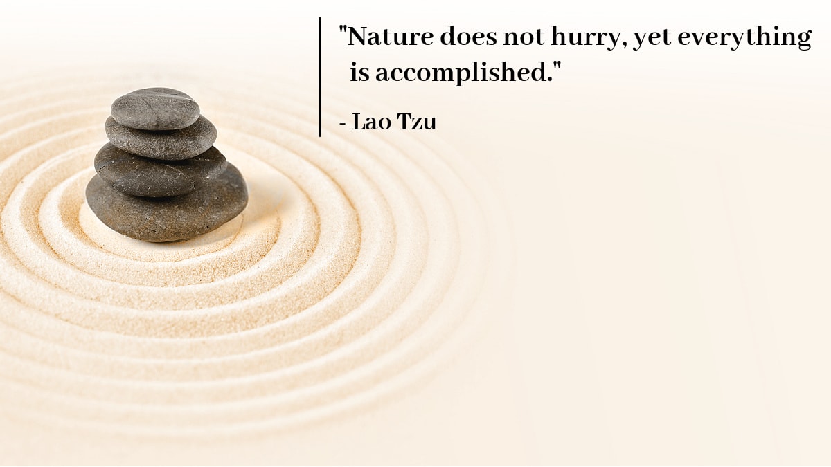 A Lao Tzu quote about slowing down next to a Zen garden rock on sand