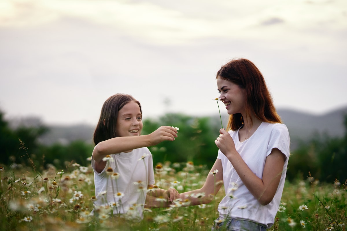 A mother and daughter practicing slowing down as they smell the flowers in a field