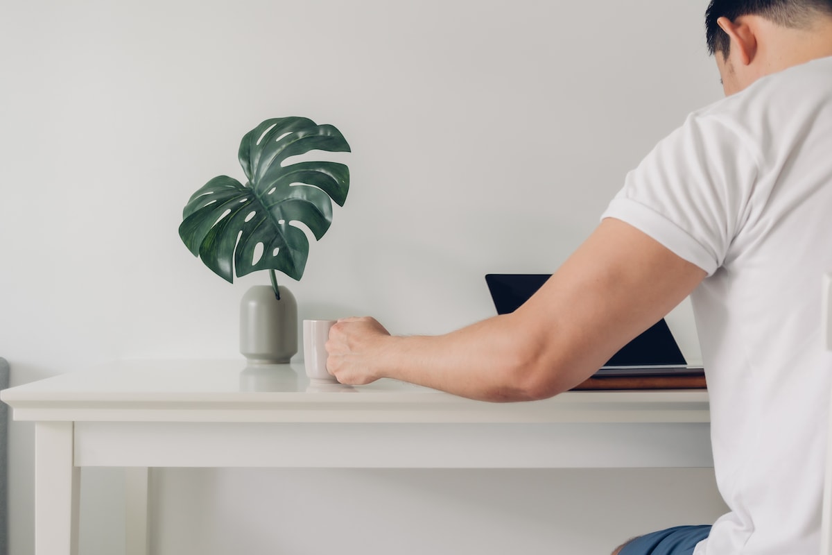 A man reading a list of extreme minimalist examples at his desk while drinking coffee