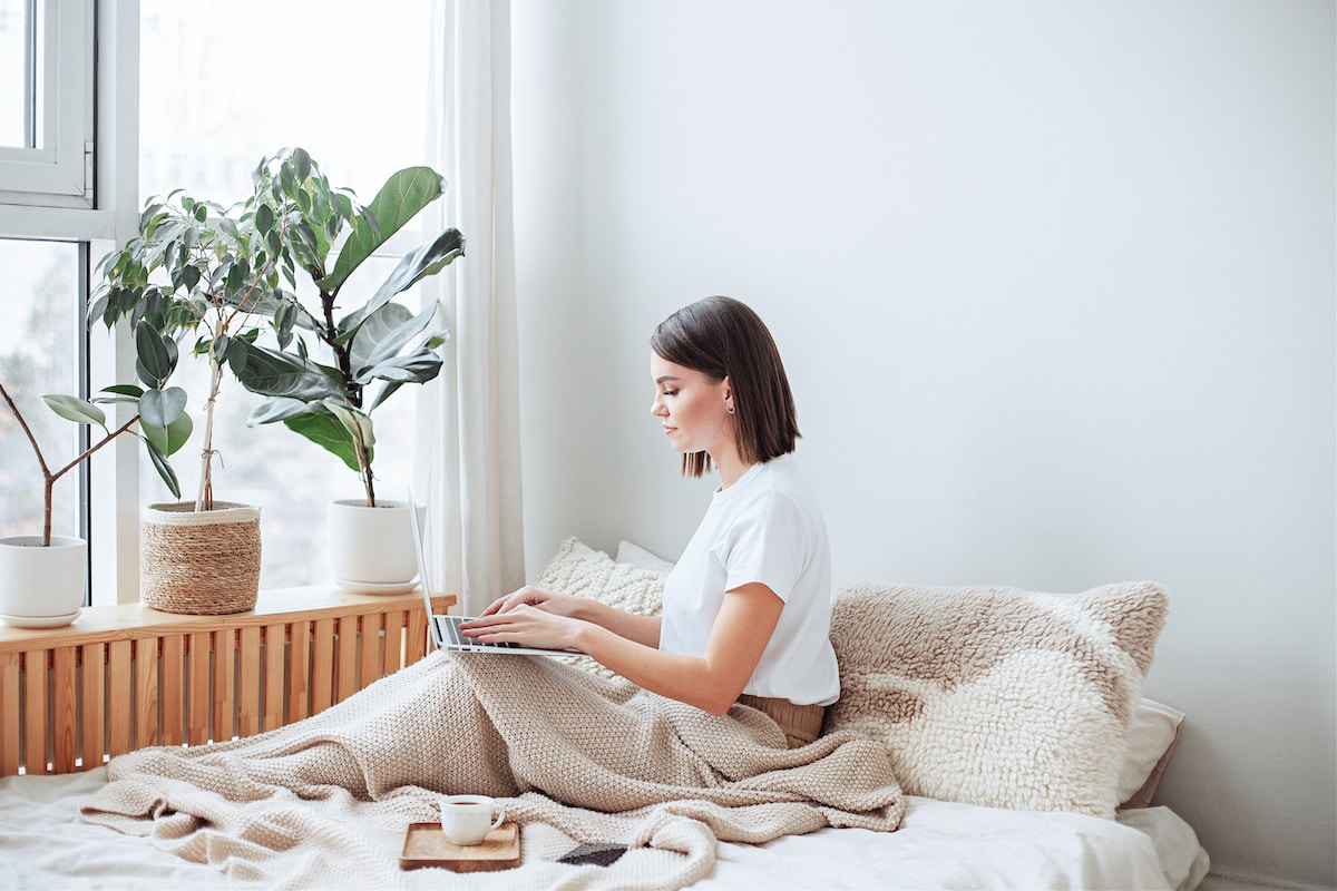 An extreme minimalist woman sitting in her furniture-free home with plants in the window