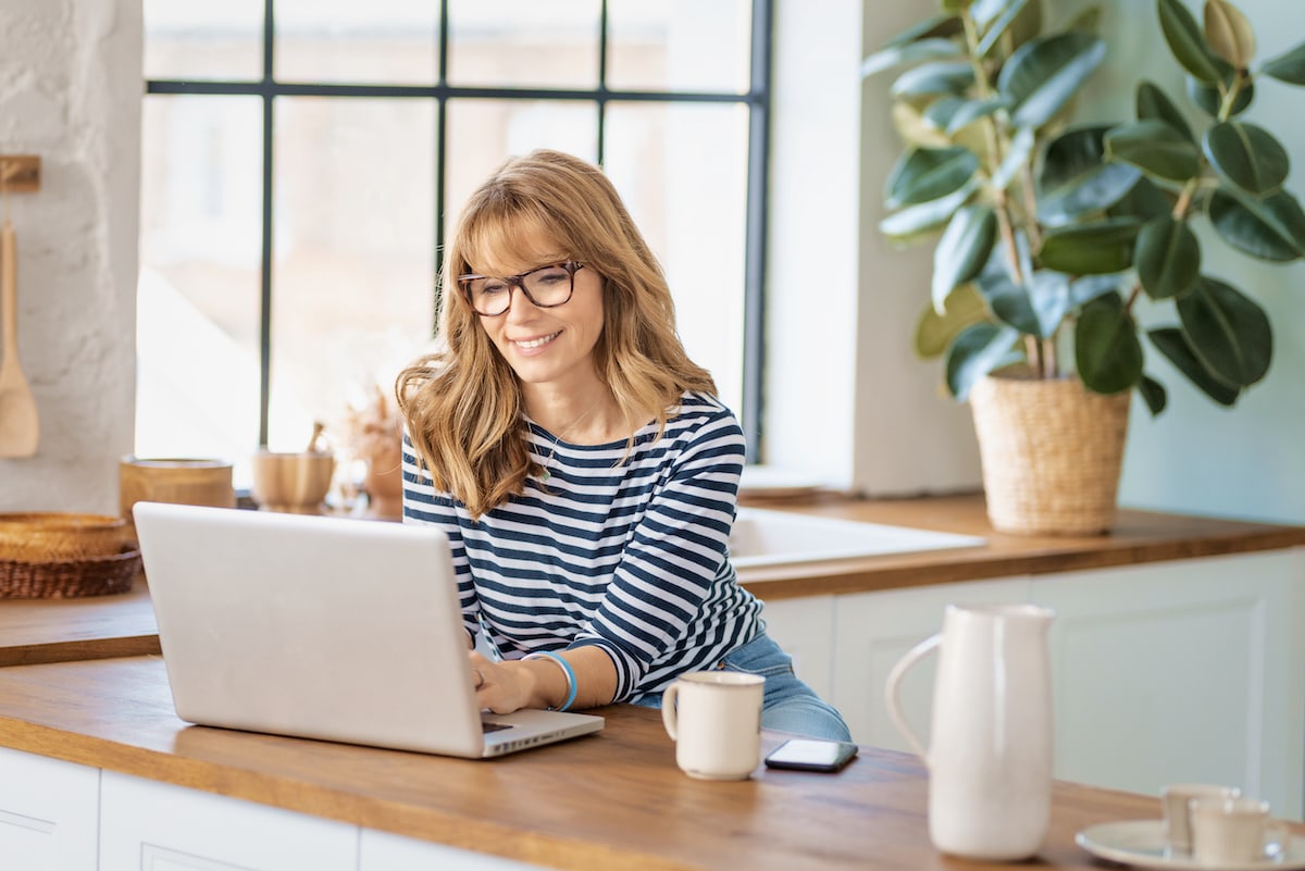 A smiling woman happy after making an intentional purchase while online shopping from her kitchen