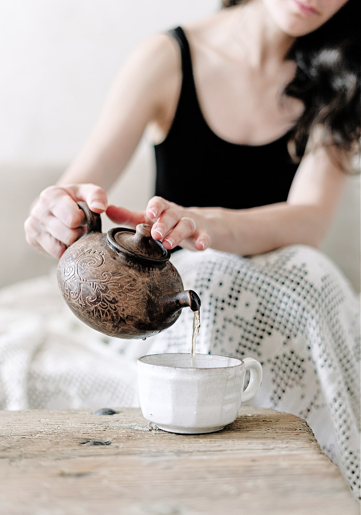 A woman reading quotes about living intentionally while pouring tea