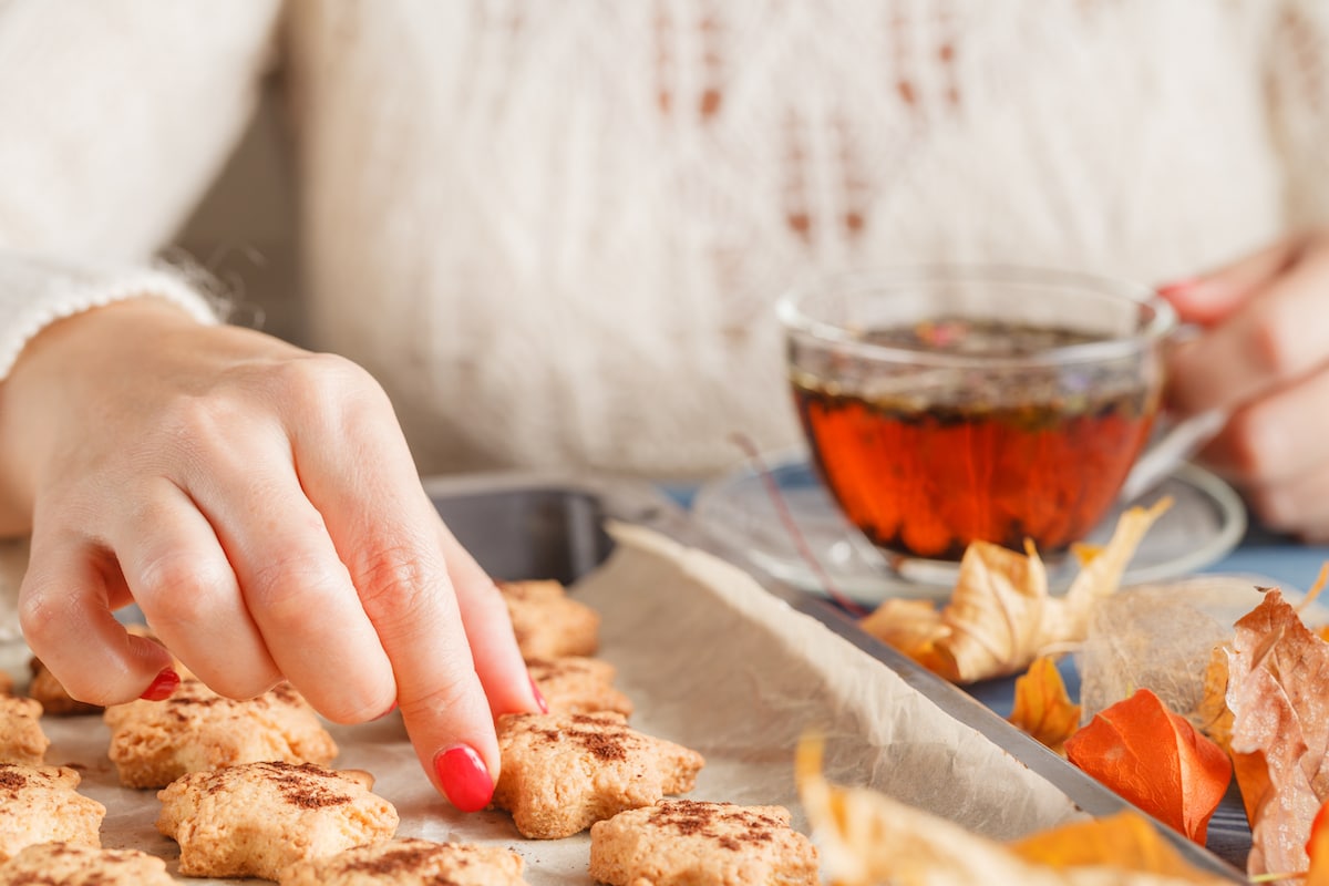 A woman enjoying her Christmas hygge gift box of cookies and tea.