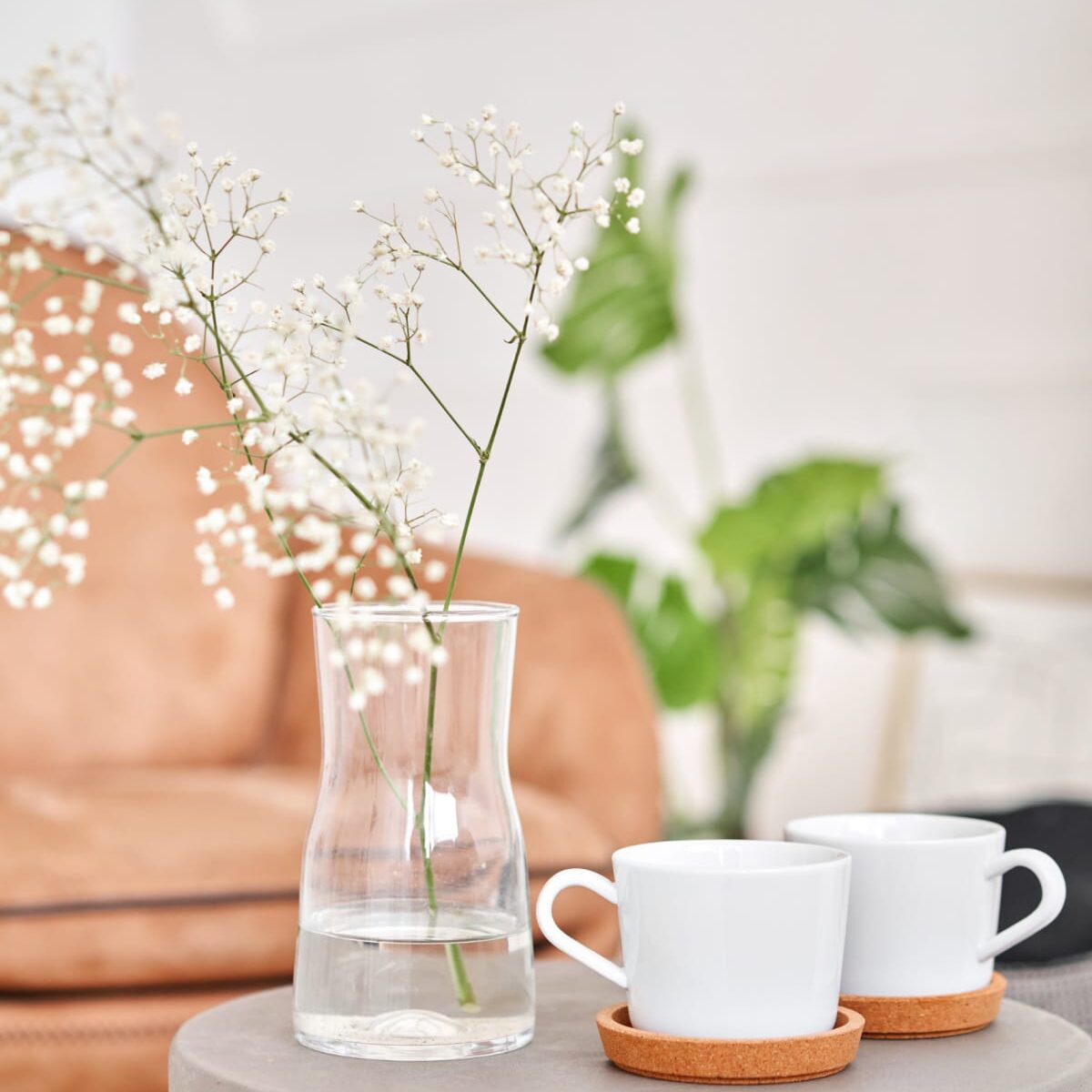 Close up of a minimalist's home with a blush chair, coffee, and plants